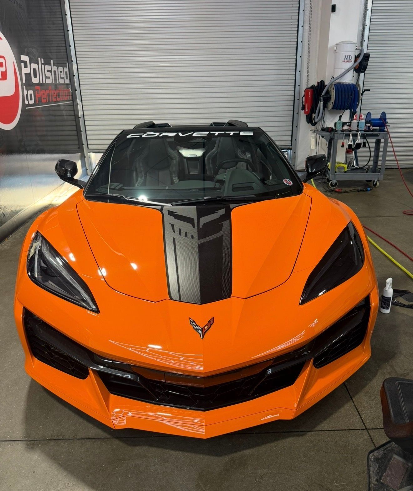 A sleek, silver Lexus car parked in a professional detailing studio with a black checkerboard floor and neon garage lights.