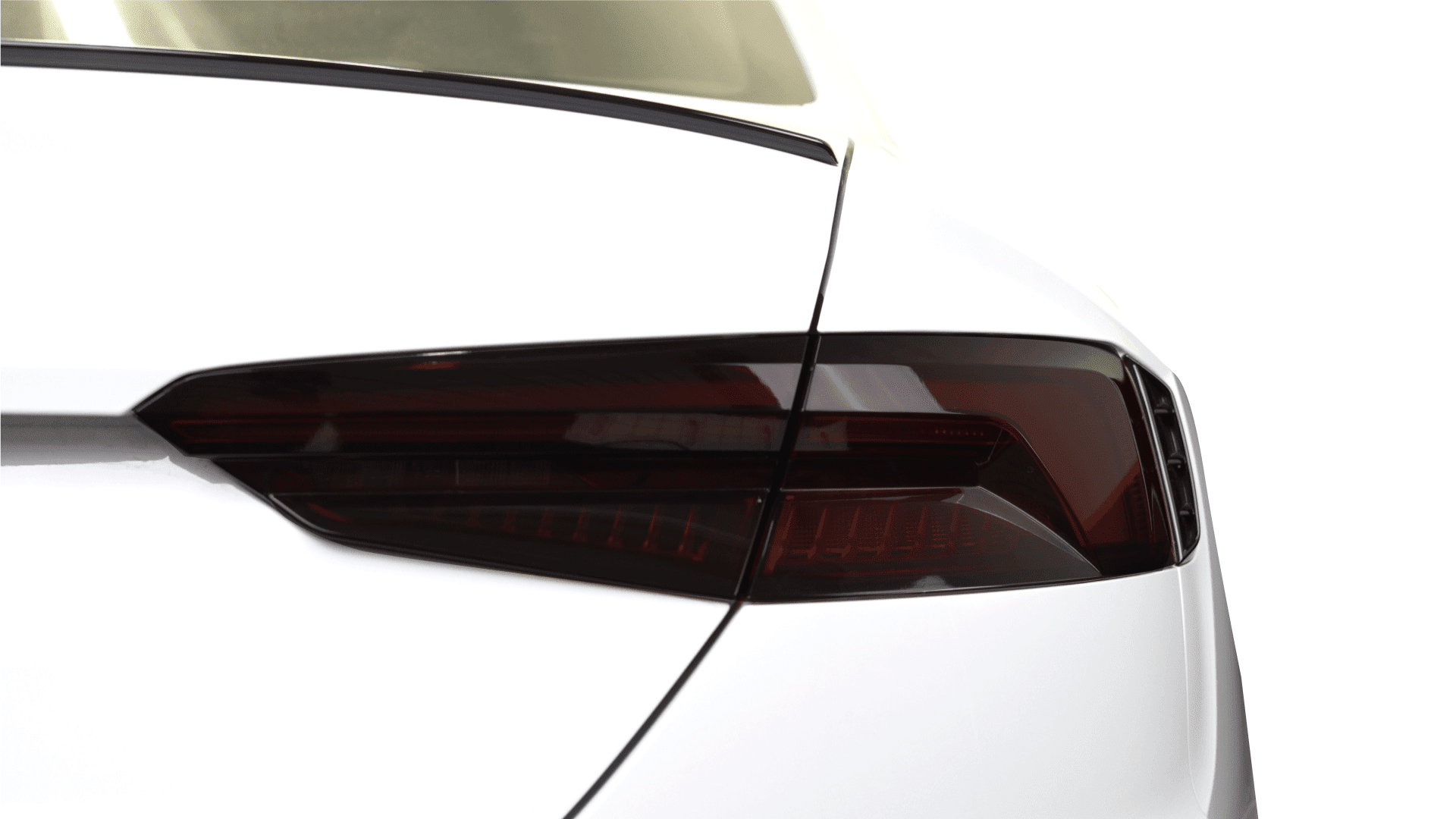 A close-up view of a dark, tinted car taillight on the rear corner of a white vehicle.