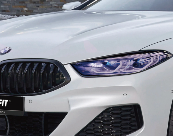 A close-up of a sleek, dark-tinted taillight on the white rear fender of a modern car.
