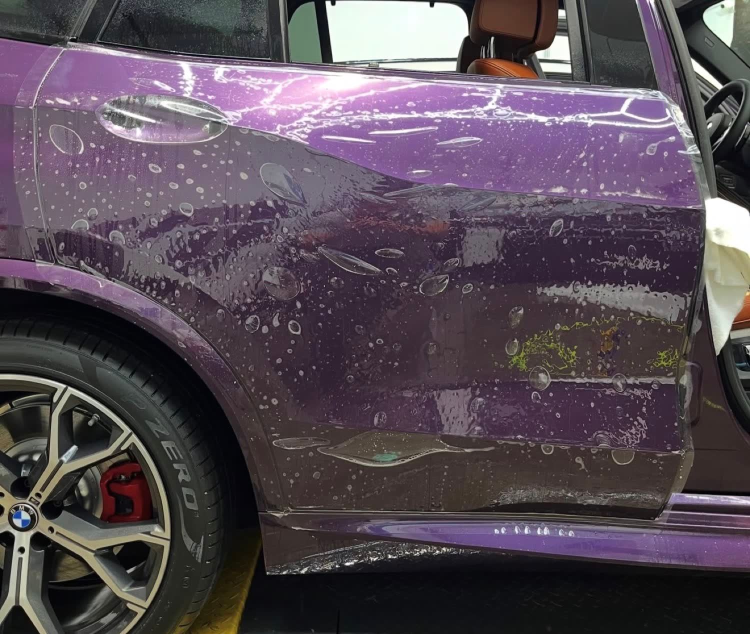 Wet installation of paint protection film on the rear door of a purple BMW X5