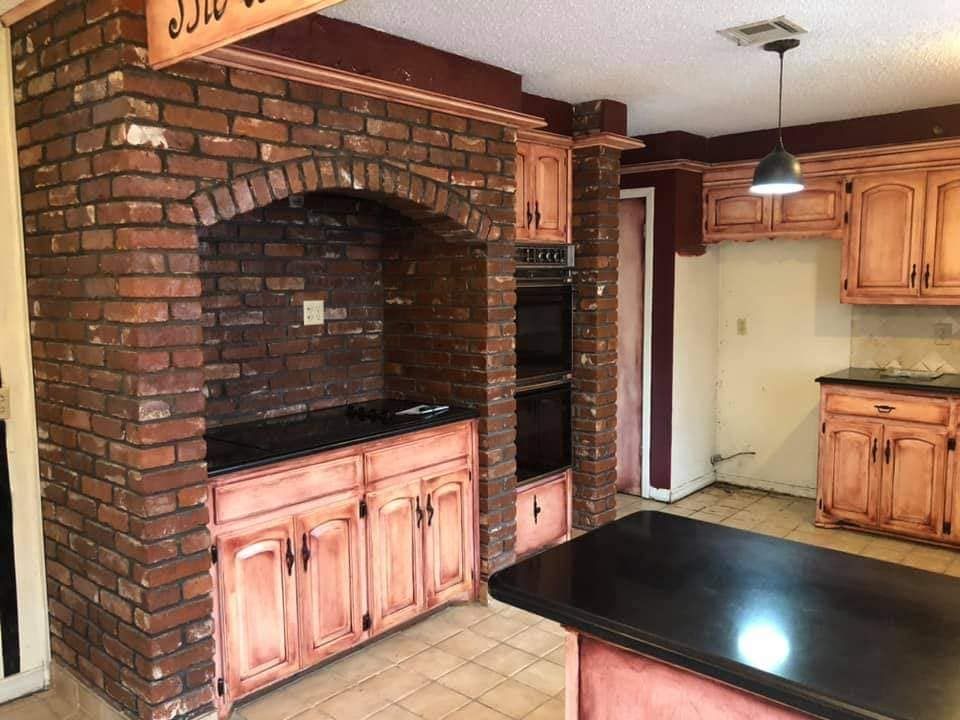 A kitchen with a brick fireplace and wooden cabinets