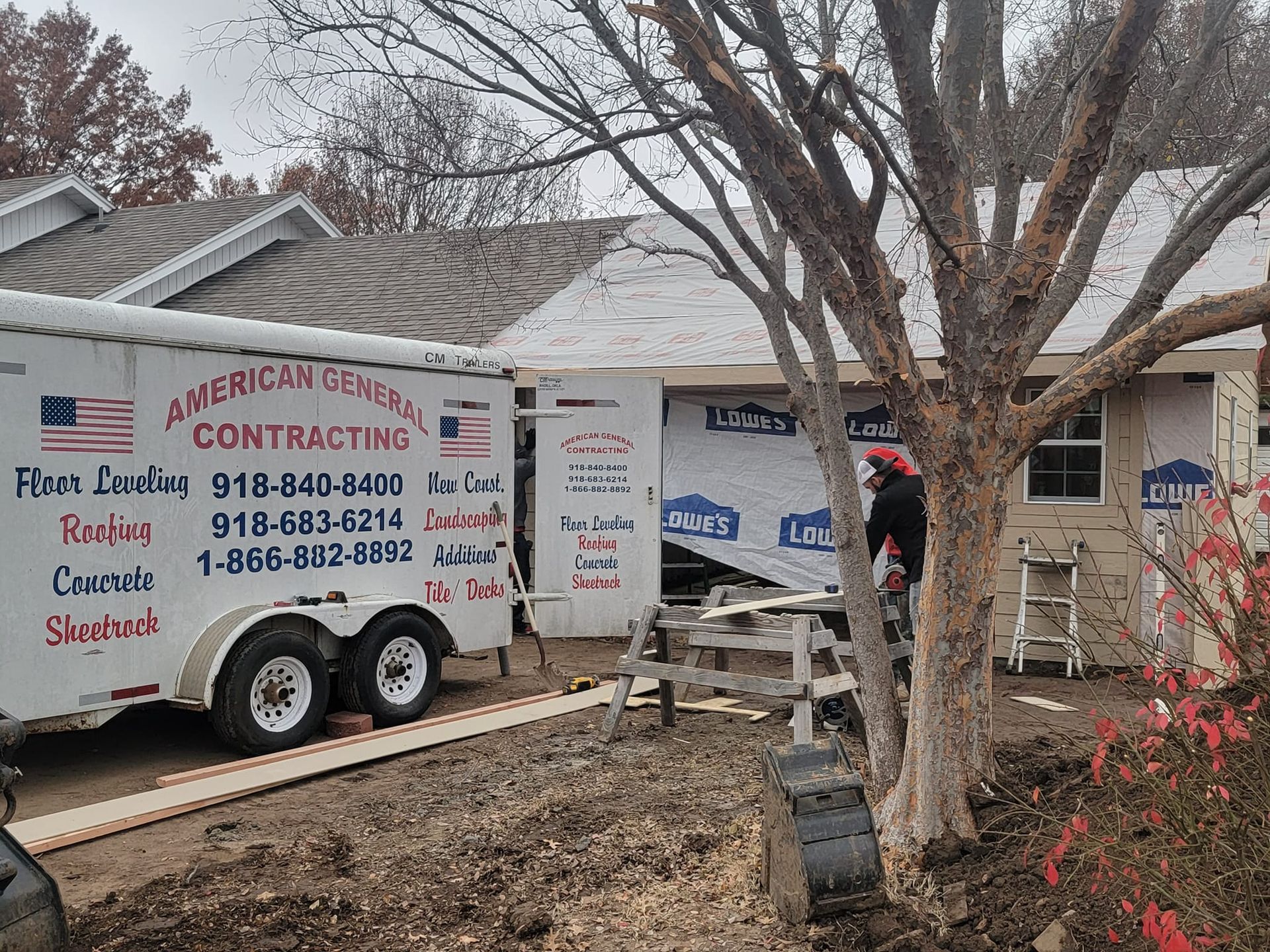 A trailer is parked in front of a house that is being remodeled.
