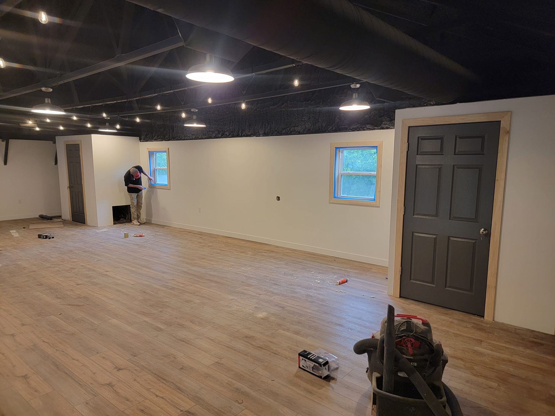 A man is standing in an empty room with a vacuum cleaner on the floor.