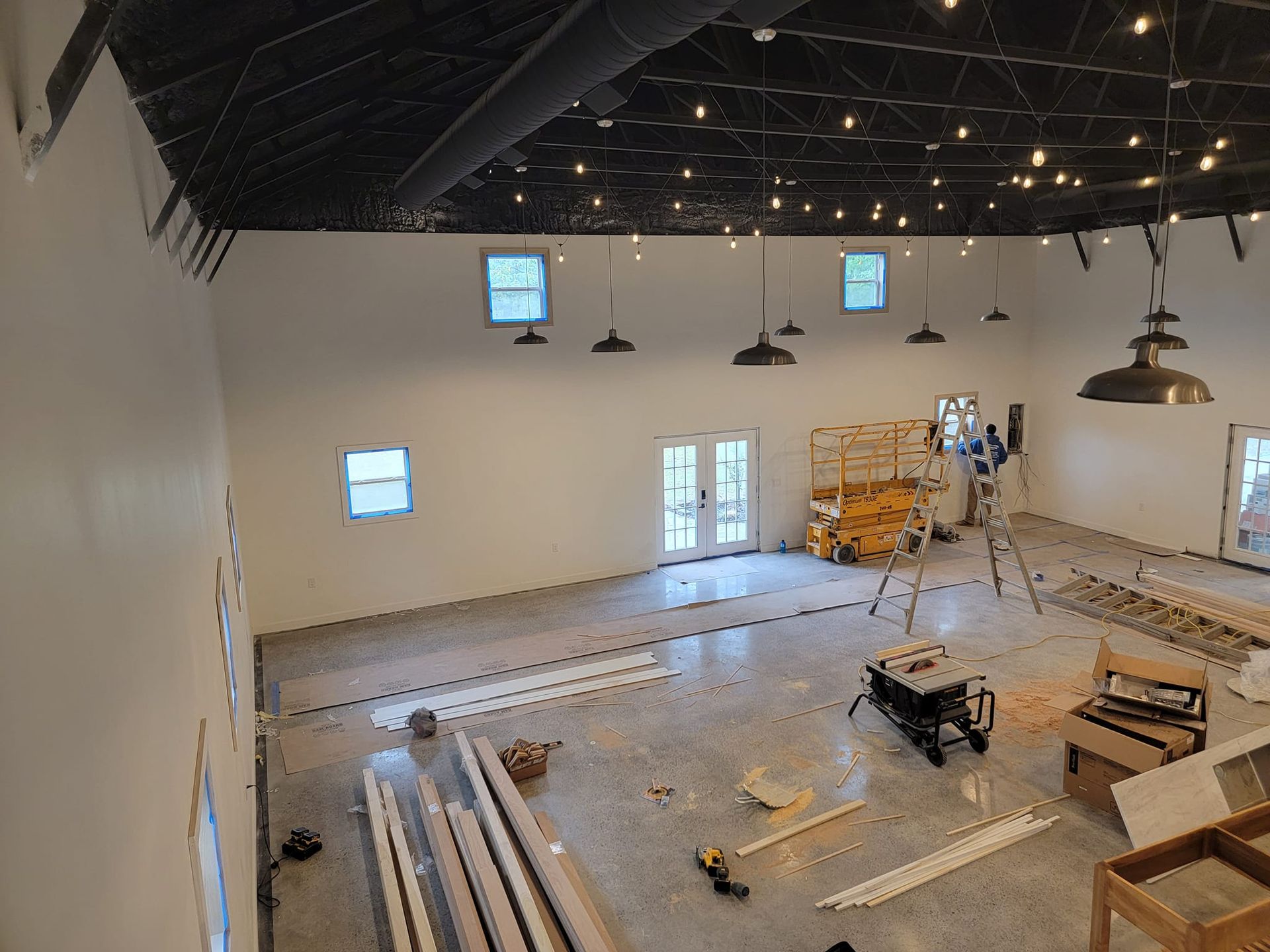 A large room with white walls and a black ceiling is being remodeled.