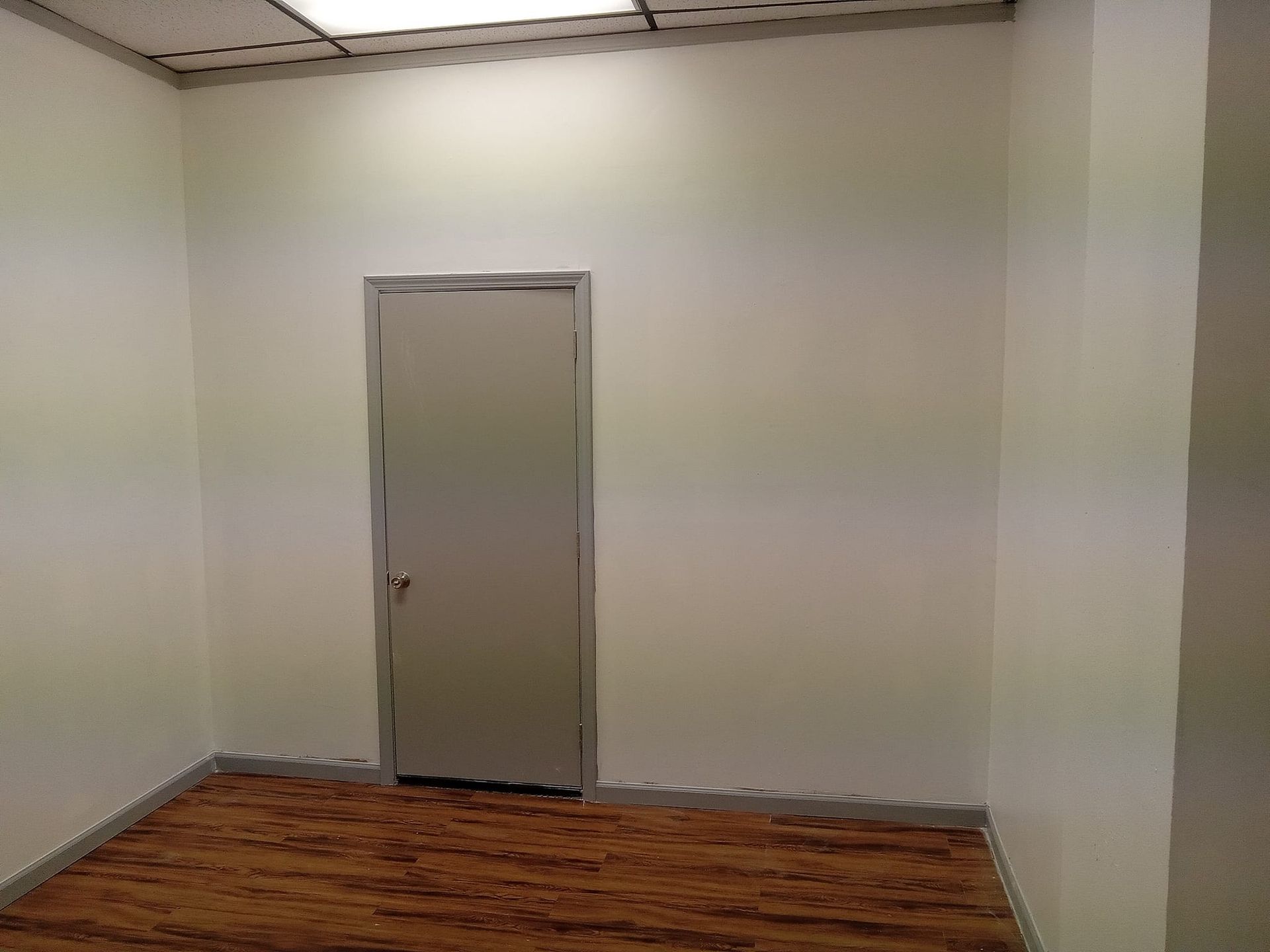 An empty room with a door and a wooden floor.