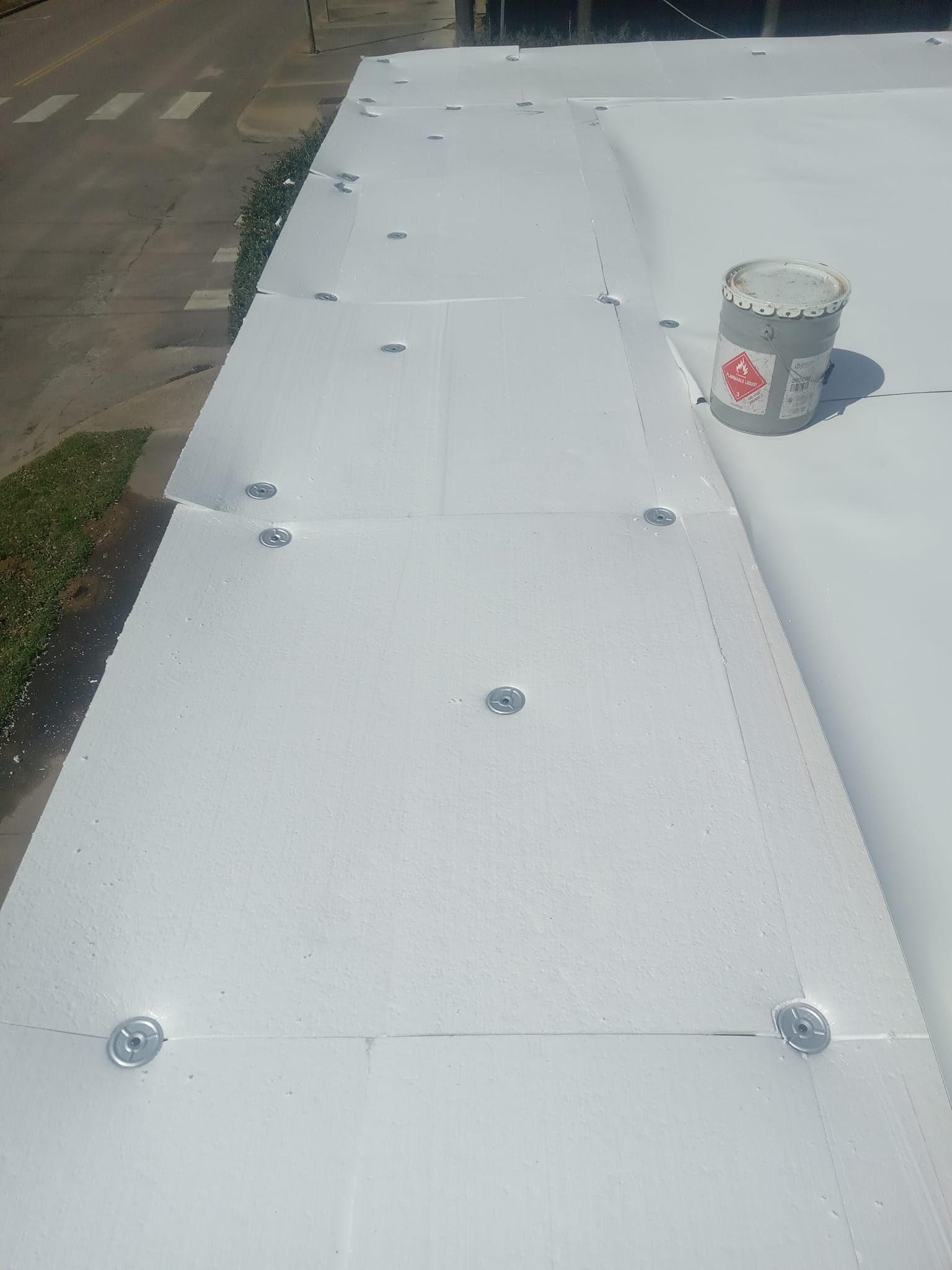 A bucket of paint is sitting on top of a white roof.