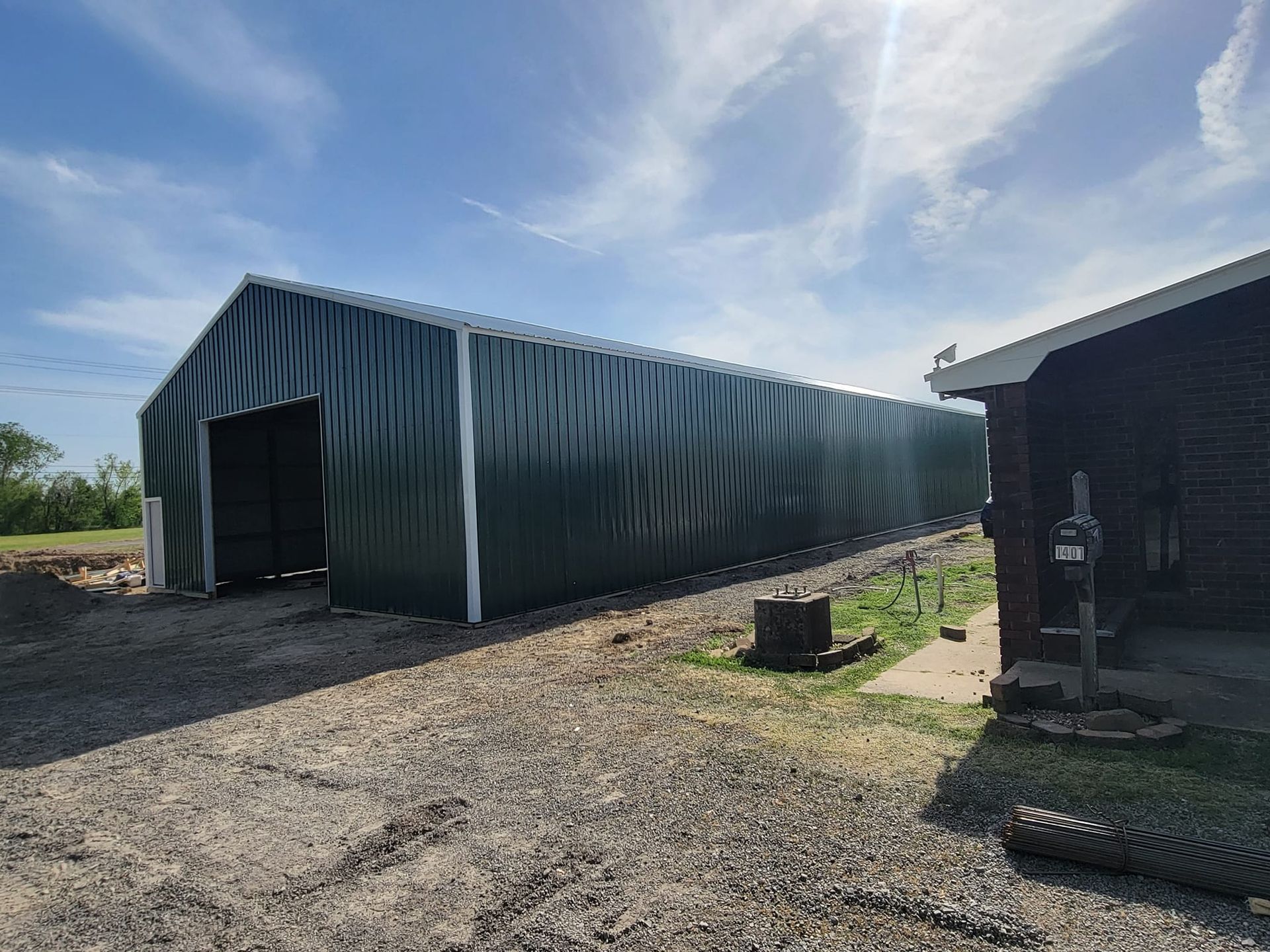 A large green building is sitting next to a house.