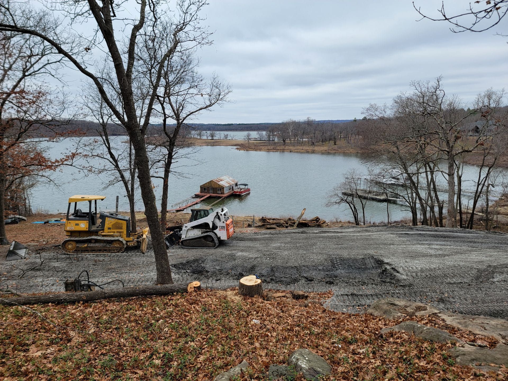 A bulldozer is parked in a dirt lot next to a lake.