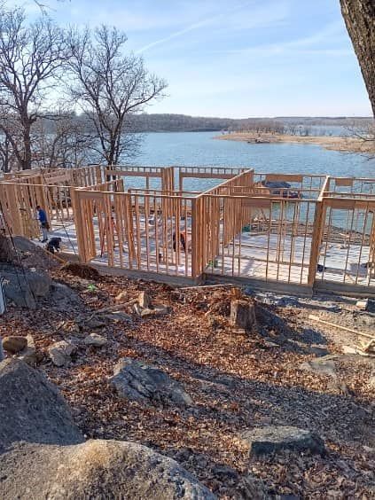 A house is being built on a hill overlooking a lake.