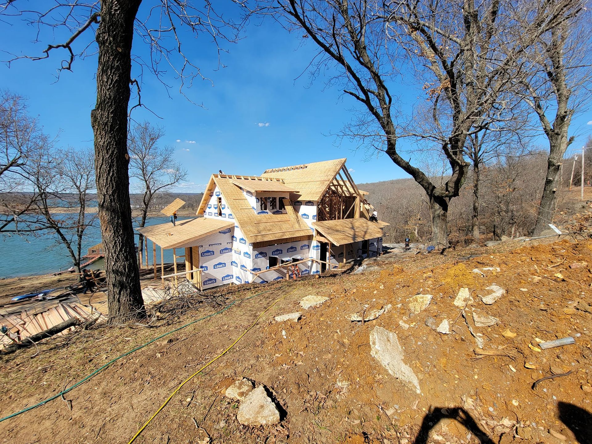 A house is being built on a hill next to a lake.