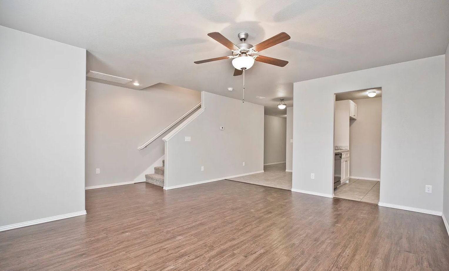 living room alternate angle showing staircase, hallway and kitchen entrance