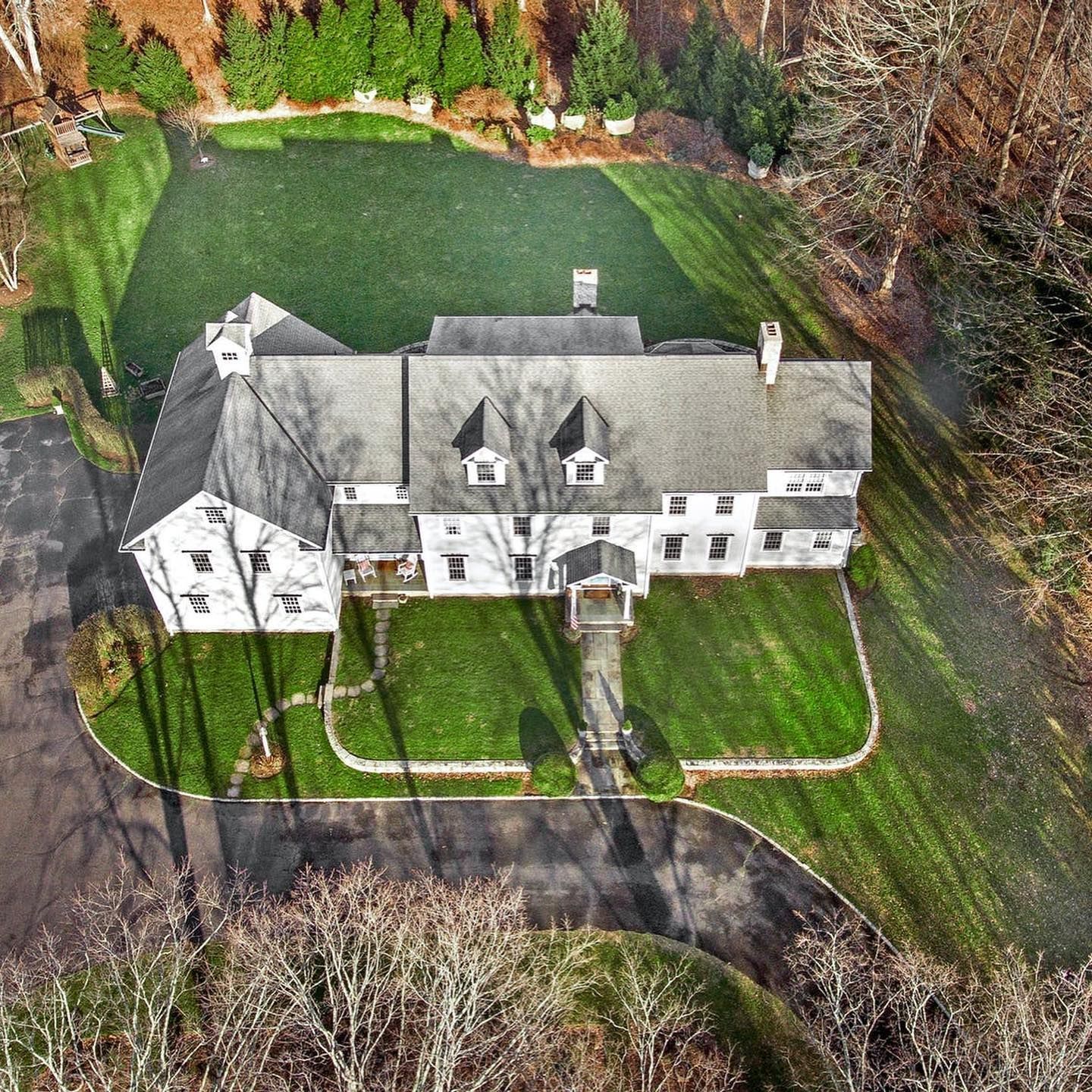 An aerial view of a large white house surrounded by trees