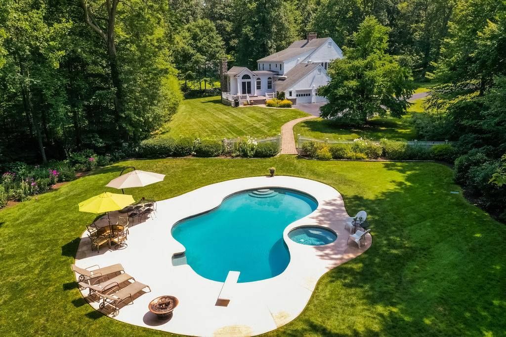 An aerial view of a large swimming pool in the backyard of a house.