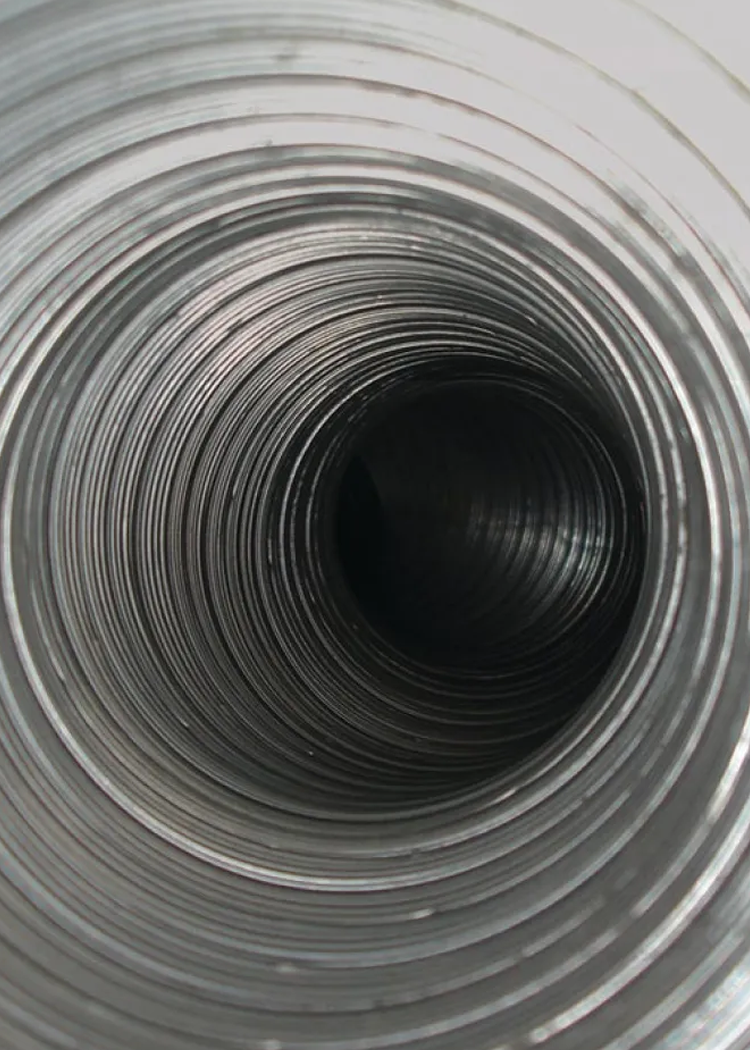 Inside view of a metallic, corrugated duct, tapering into darkness.