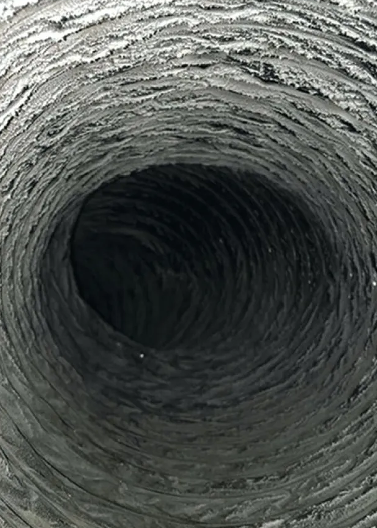 Interior of a flexible, corrugated air duct, with a dark, circular opening.