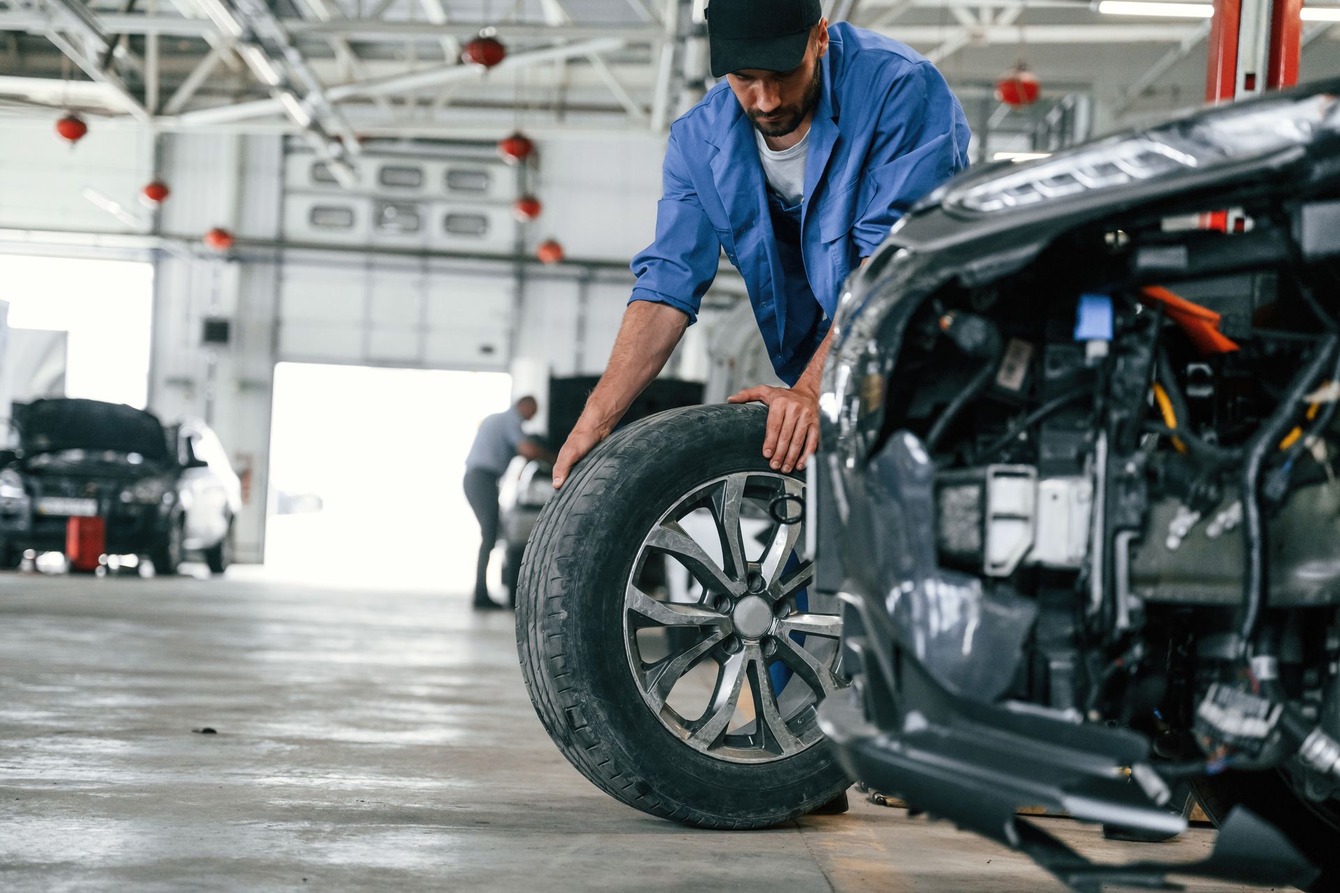 A man is changing a tire on a car in a garage.