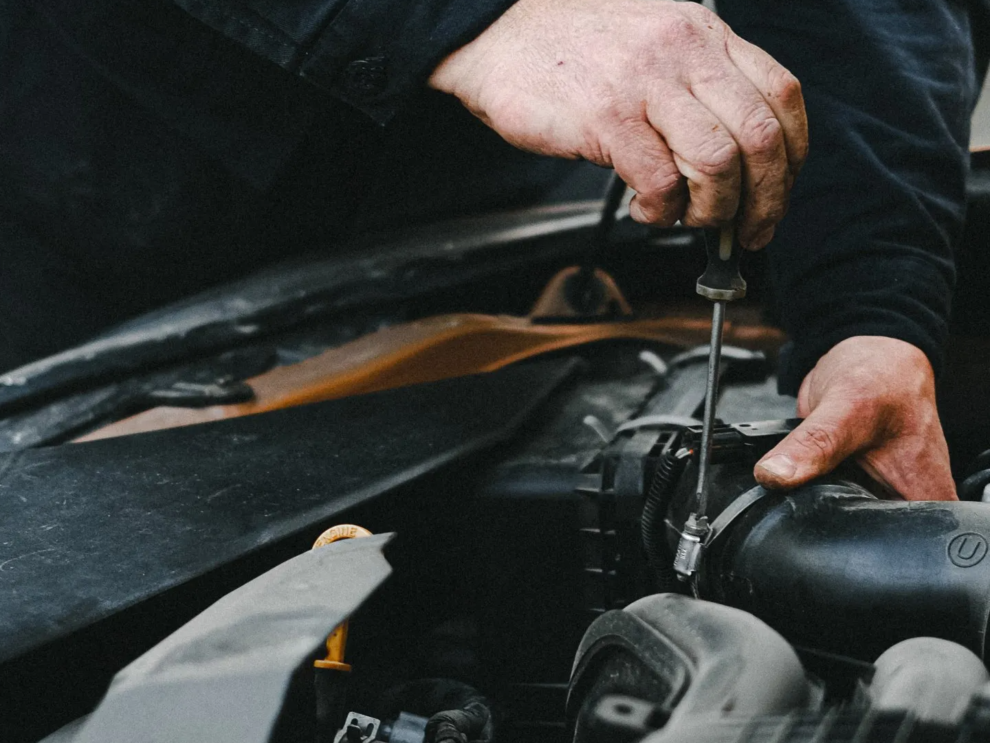 A man is working on a car engine with a screwdriver | Work with JCR Performance for Car Engine Repairs in Sacramento, CA