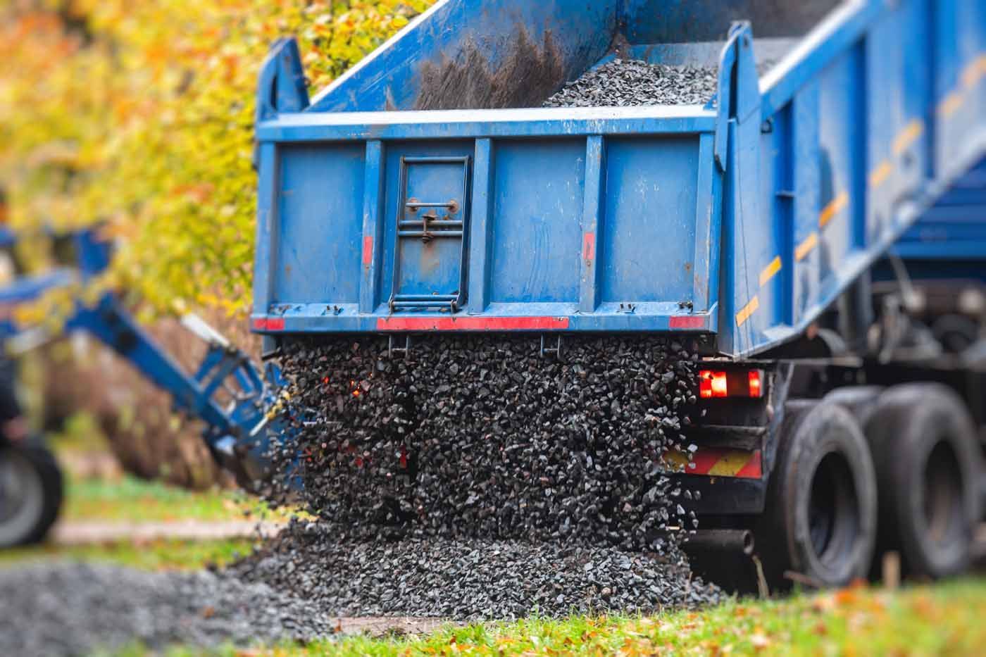 A blue dump truck is being loaded with gravel.