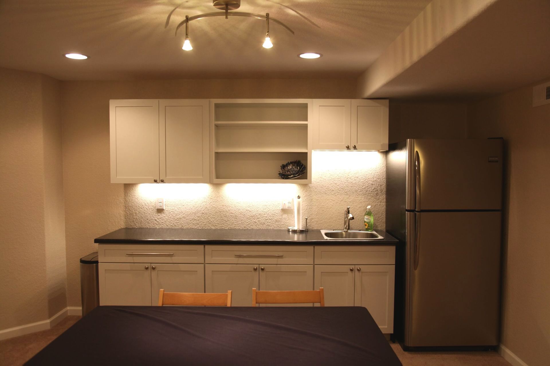 A kitchen with white cabinets and a stainless steel refrigerator