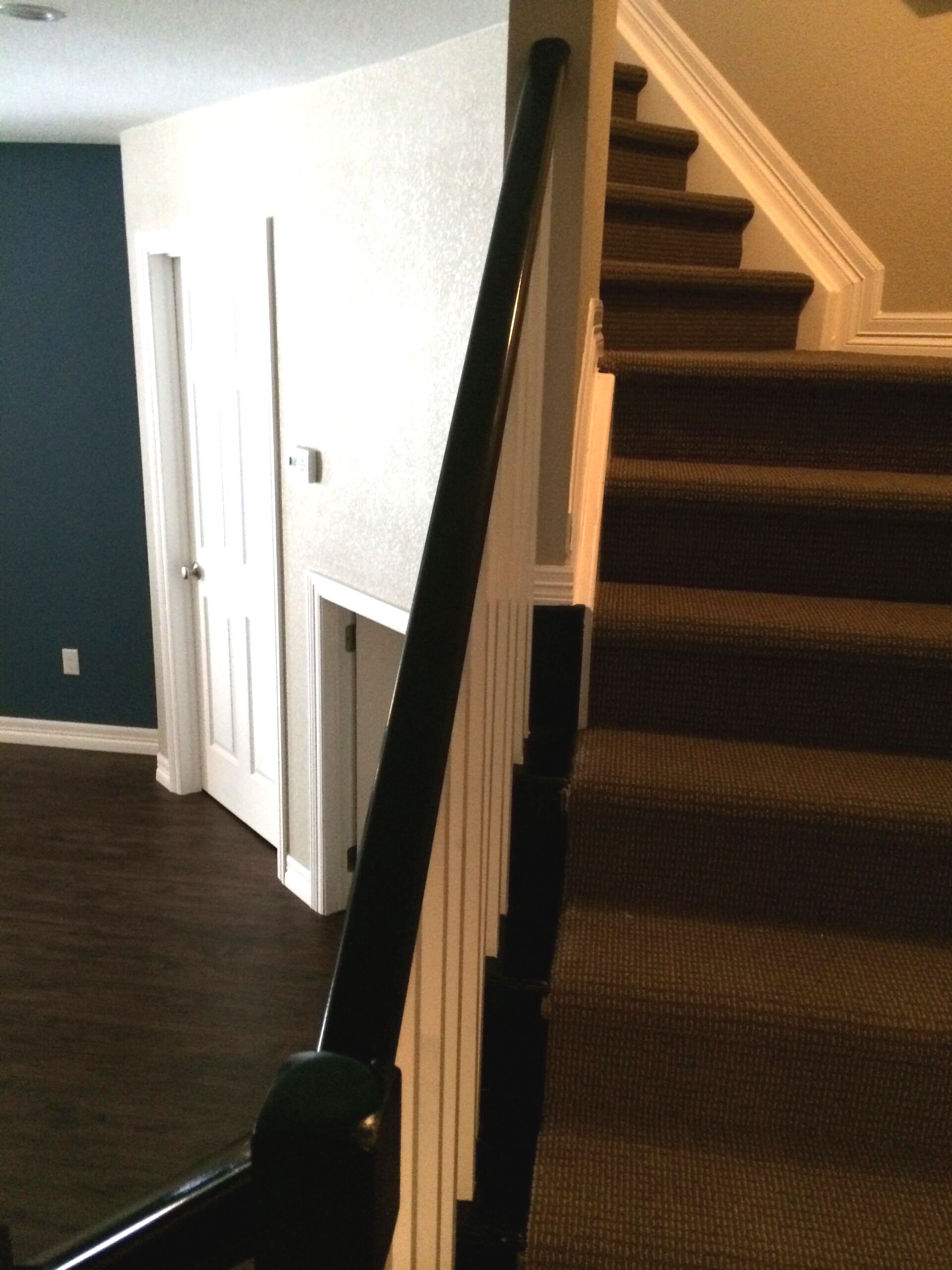 A staircase with brown carpet and a black railing