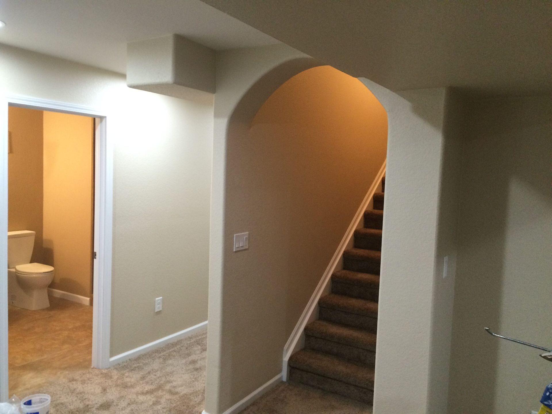 A basement with stairs leading up to the second floor and a toilet.
