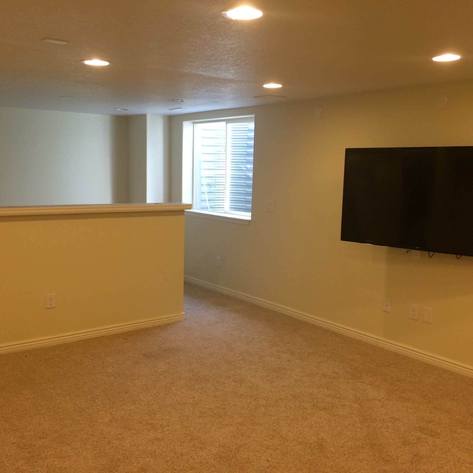 An empty room with a flat screen tv on the wall