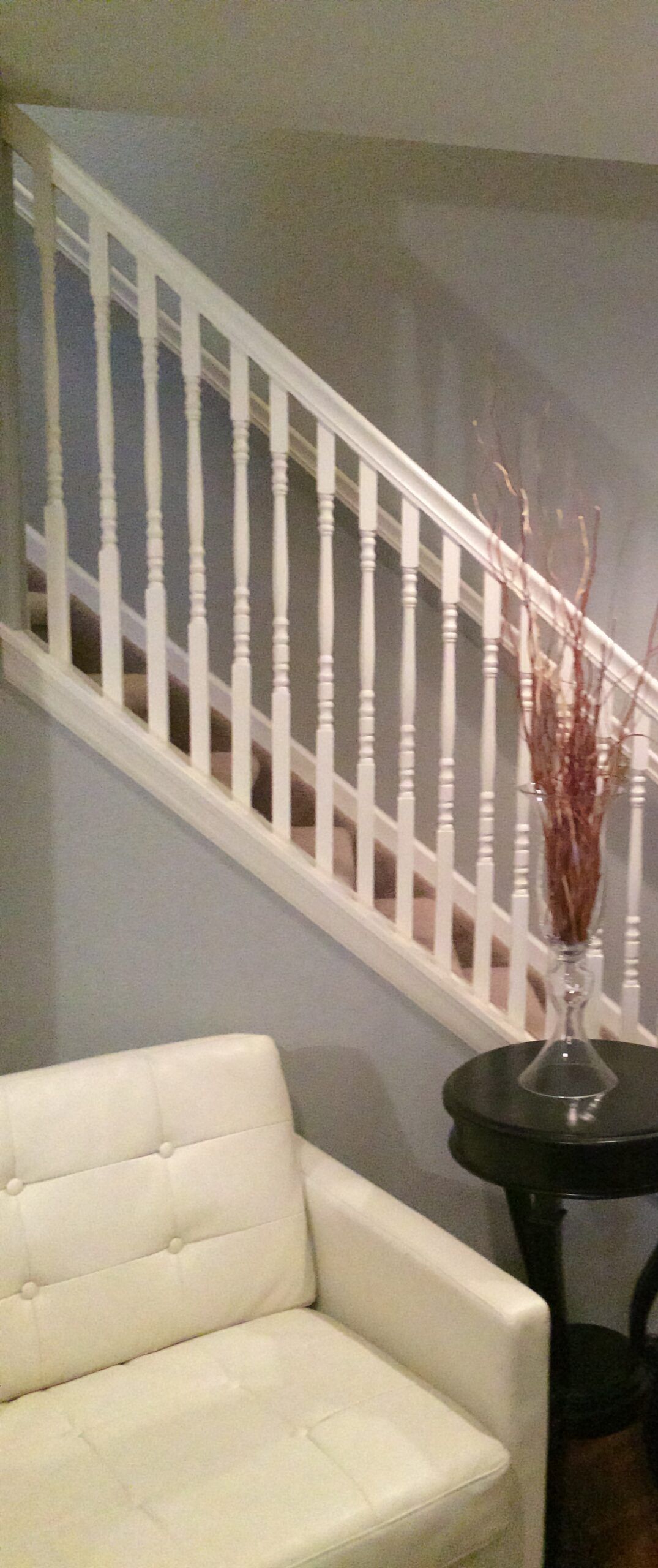 A living room with a white couch and stairs