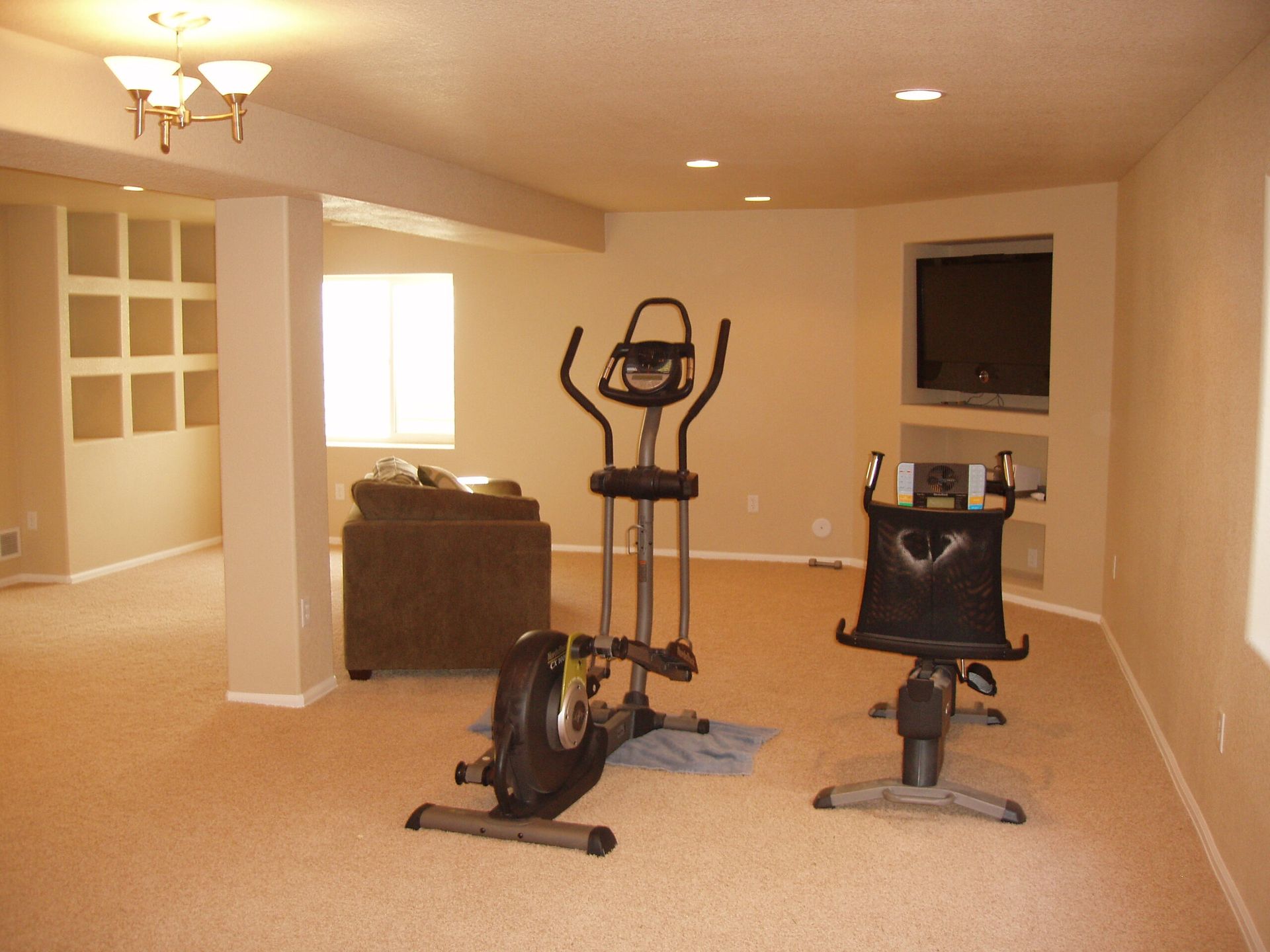 A basement with two exercise bikes and a television