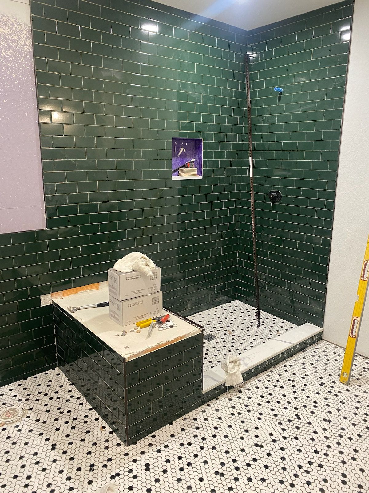 A bathroom with green tiles and a walk in shower.