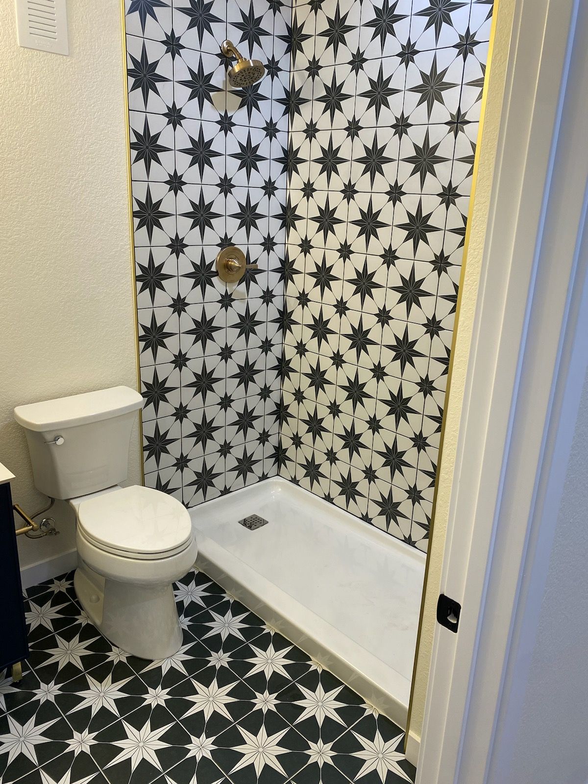 A bathroom with a toilet , shower and black and white tiles