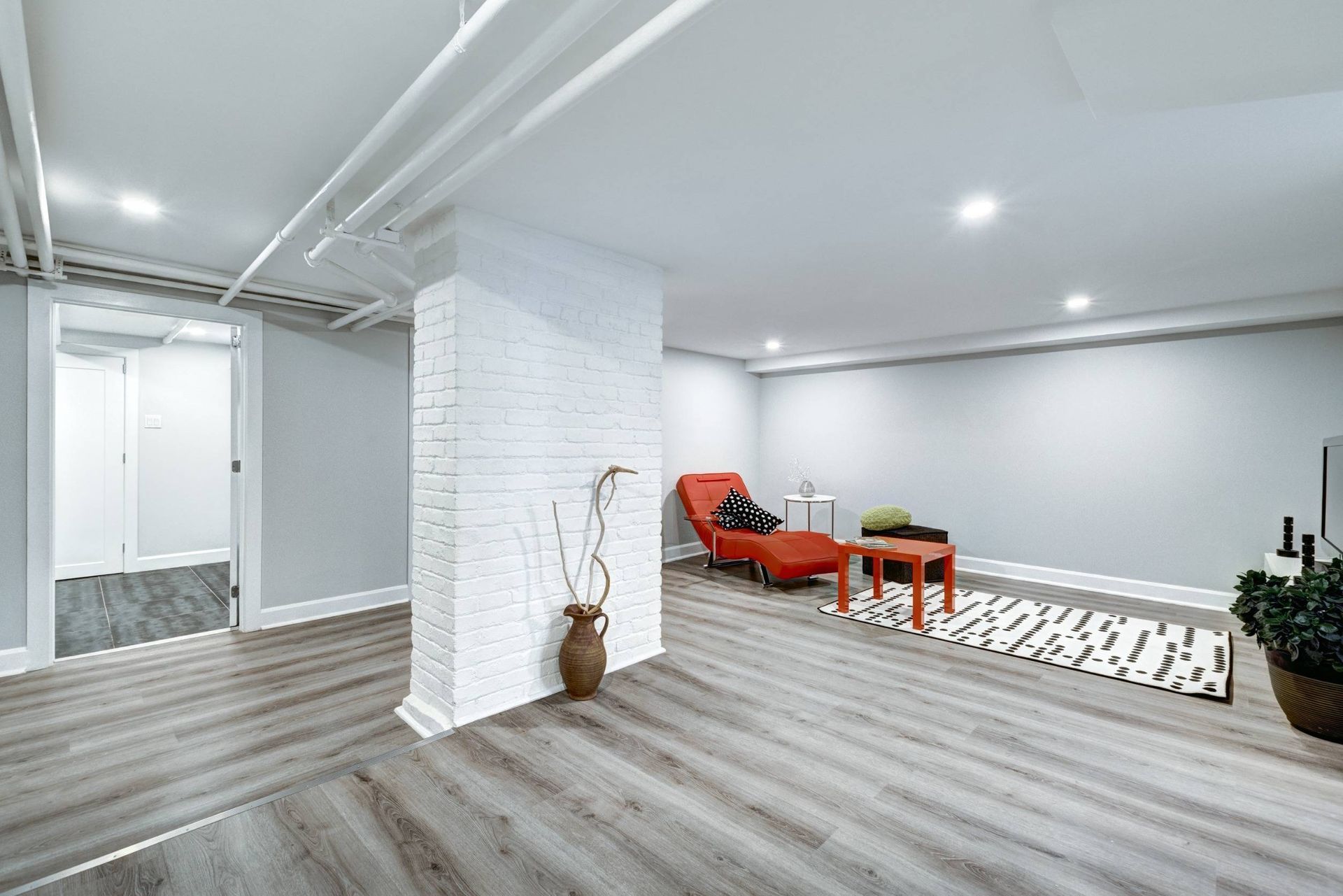 A basement with stairs , a table and a shovel hanging on the wall.