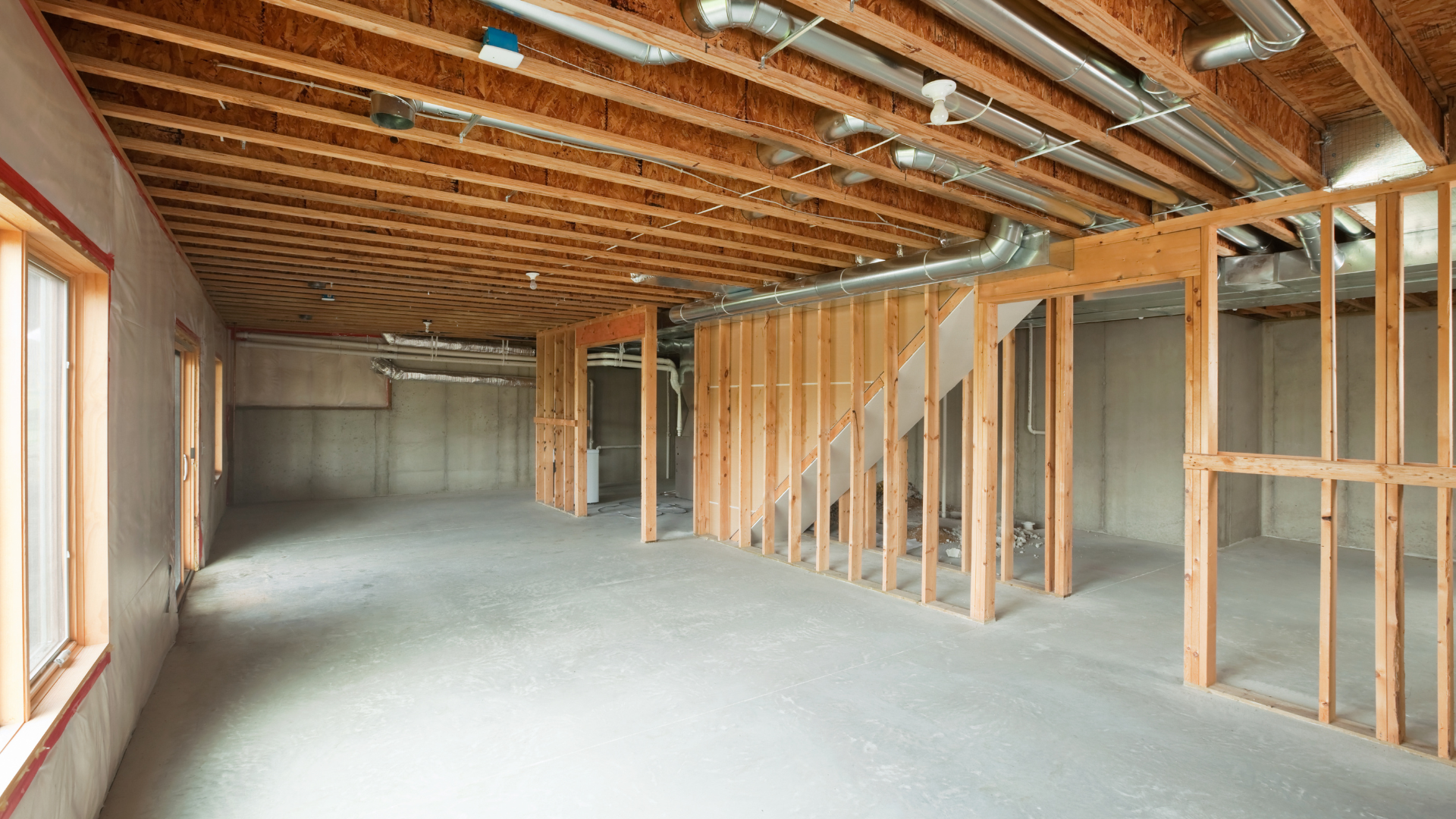 An empty basement under construction with wooden beams and a staircase.