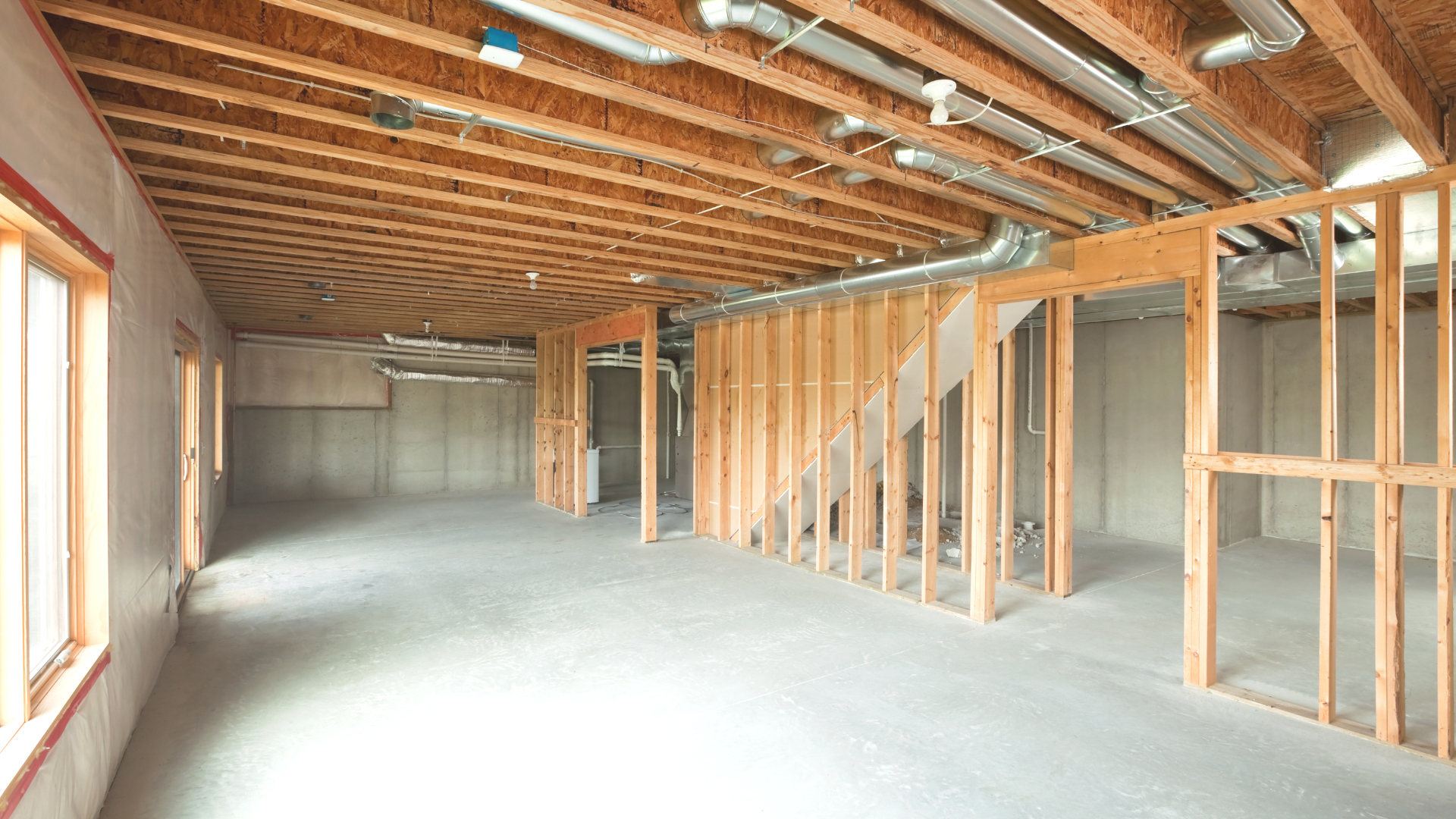 An empty basement under construction with wooden beams and a staircase.