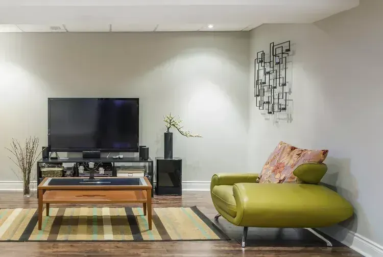 A living room with a television , chair , coffee table and rug.