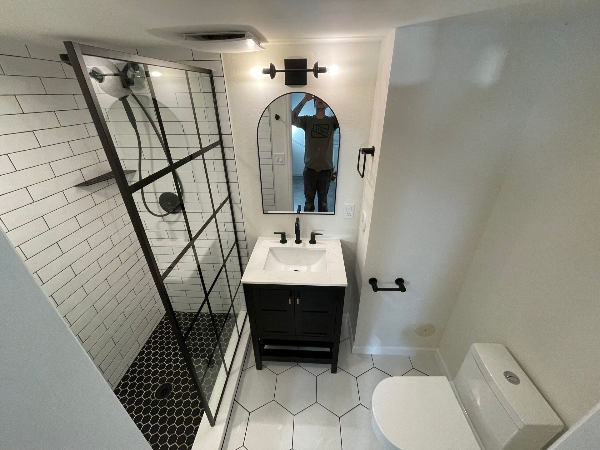 A bathroom with a sink , toilet , shower and mirror.