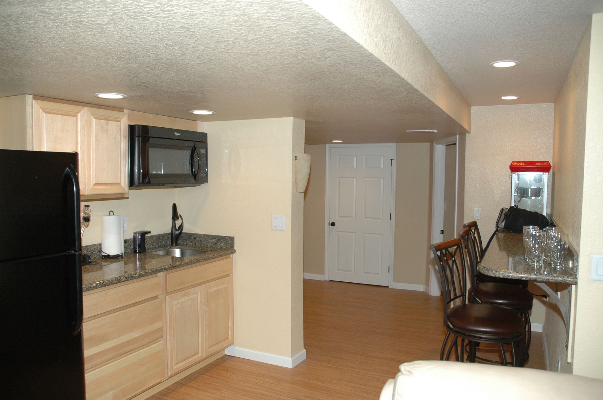 A kitchen in a basement with a black refrigerator