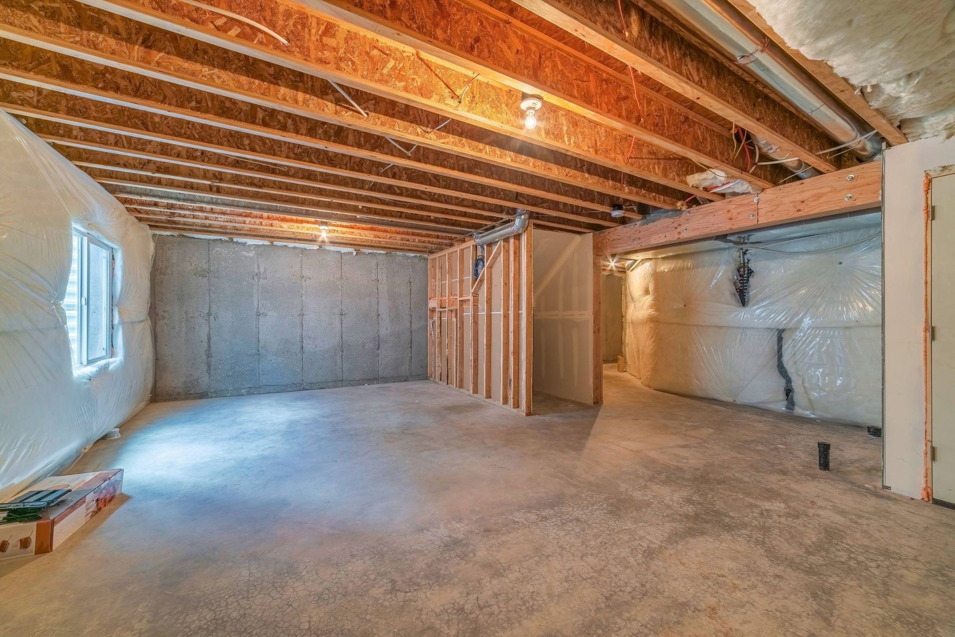 An empty basement with a wooden ceiling and concrete floor.
