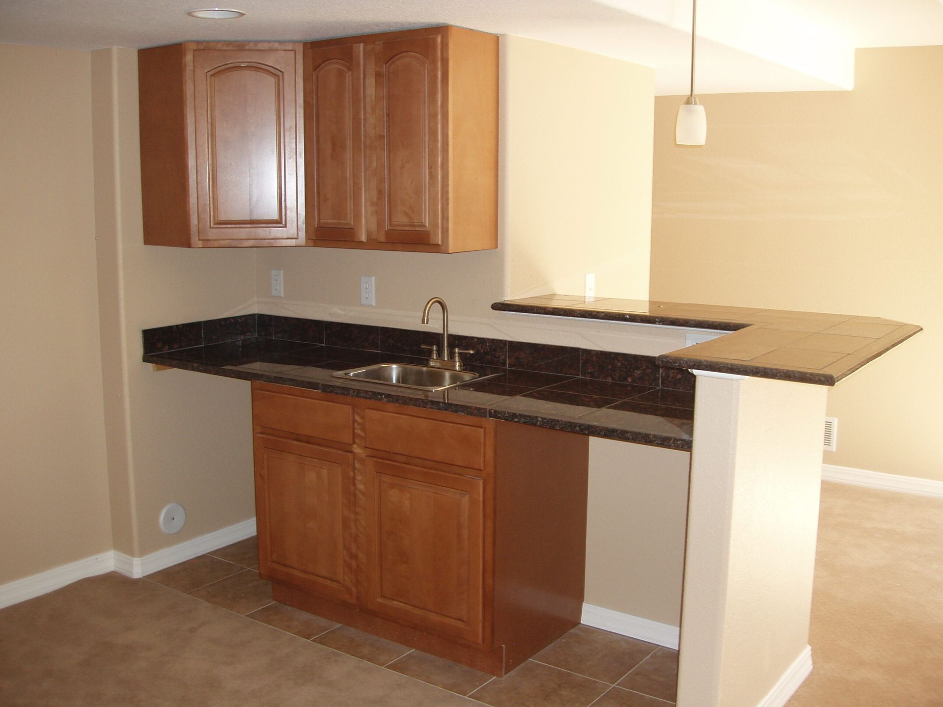 An empty kitchen with wooden cabinets and granite counter tops