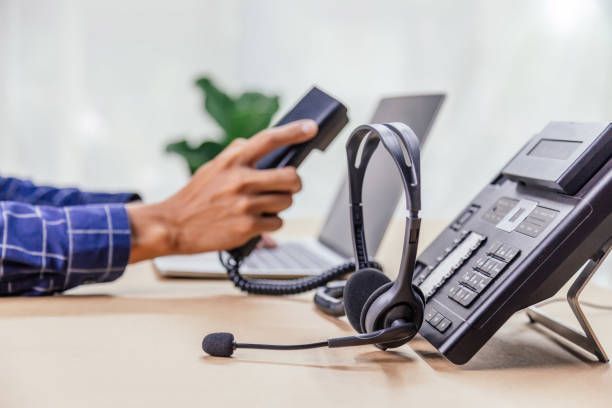 A man is holding a telephone device with VOIP headsets in the office