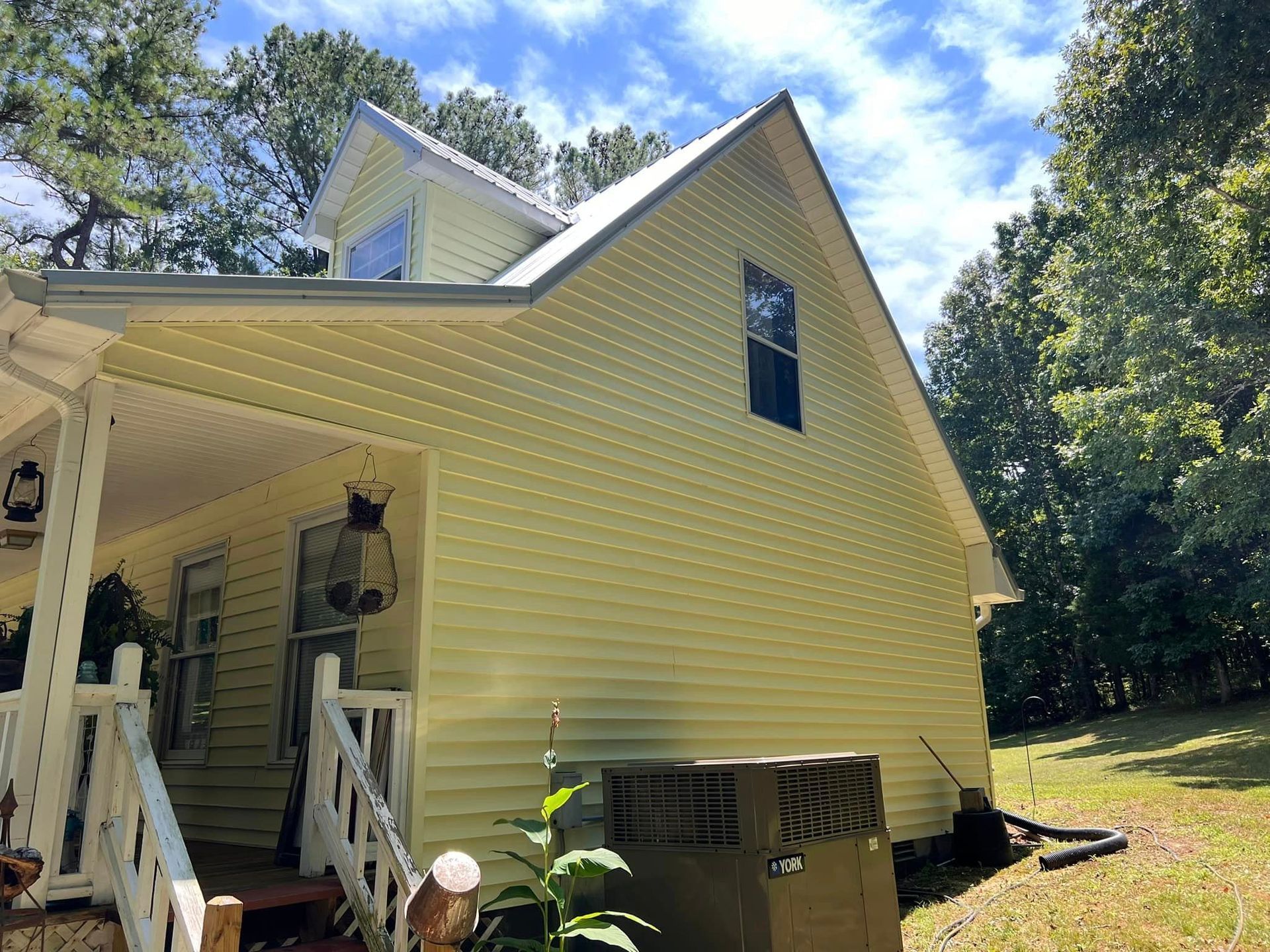 A person is using a high pressure washer to clean the side of a house.