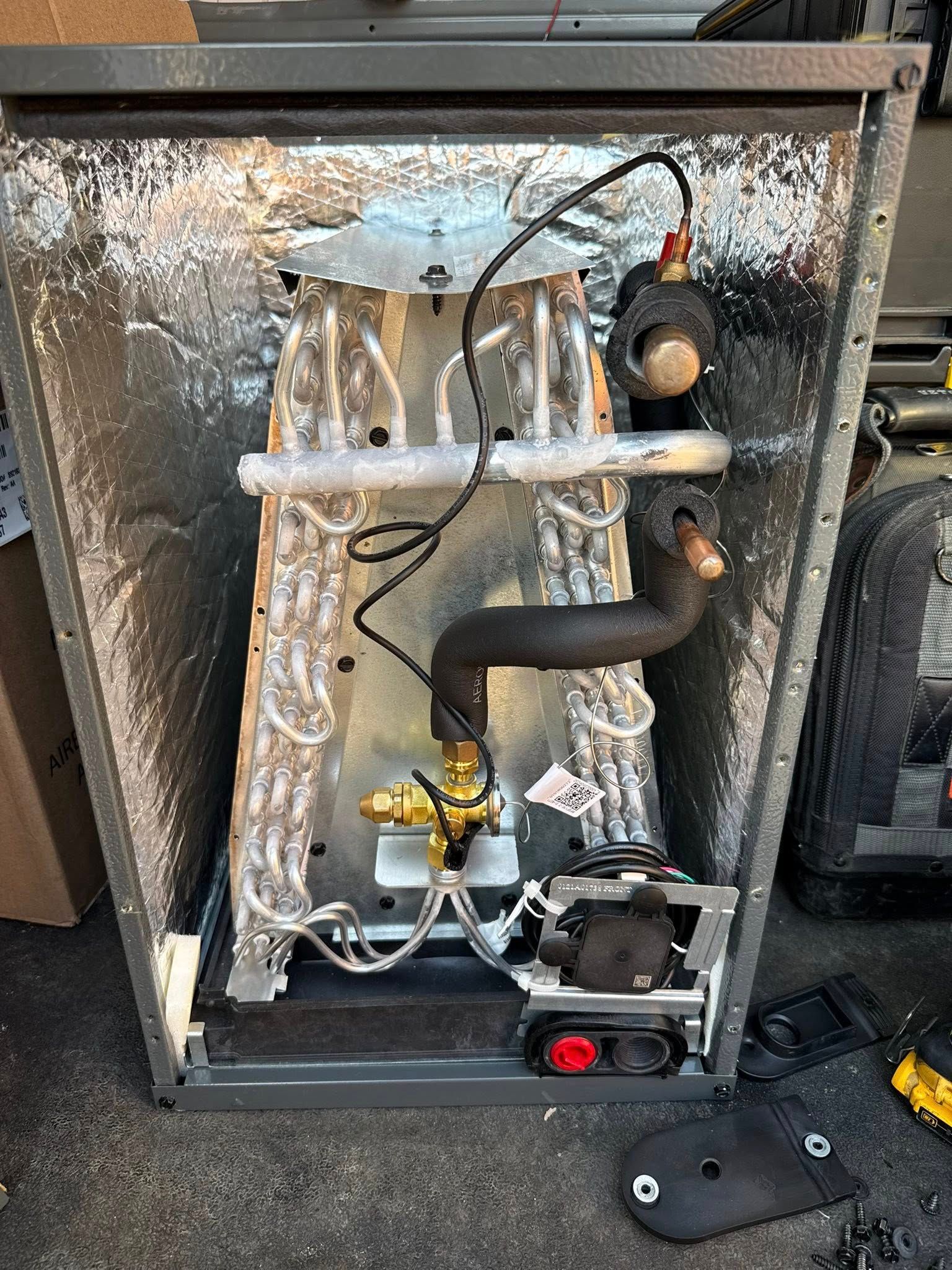 Skyline Comfort Services LLC - HVAC unit interior, with copper coils, valve, and insulation. Metal frame with mechanical.