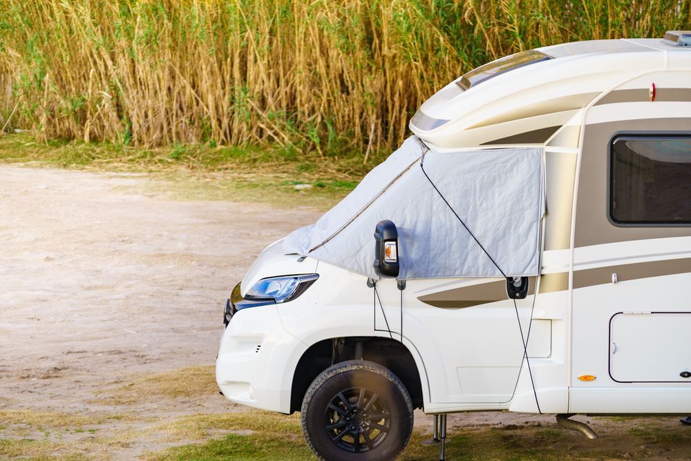 White RV with gray sunshade parked outdoors.