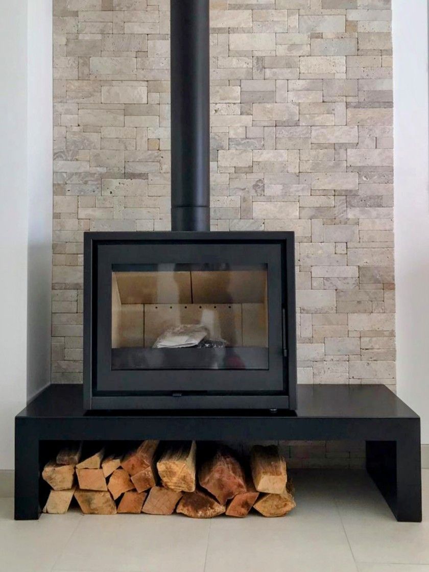 une cheminée avec une pile de bûches en dessous