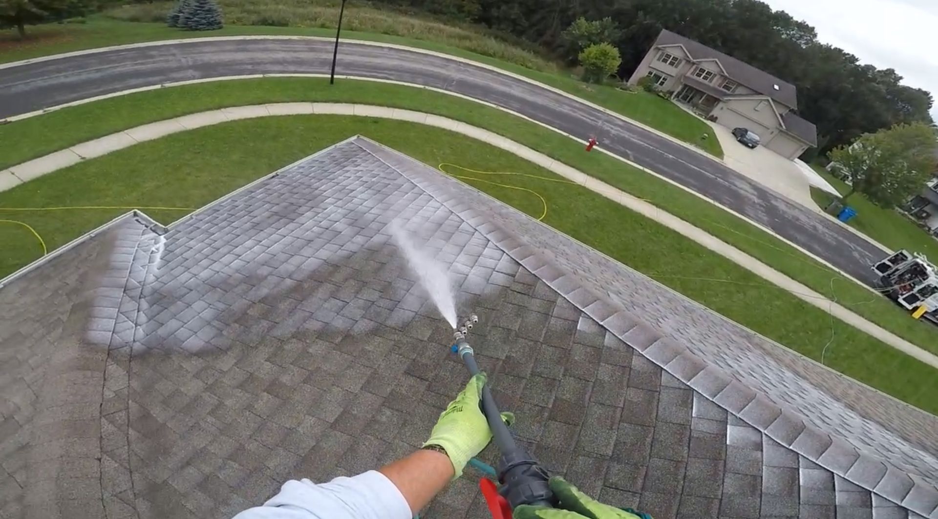 A person is cleaning a roof with a high pressure washer.