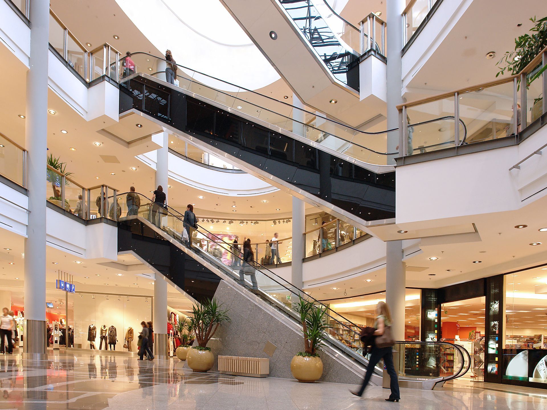 A woman is walking down an escalator in a shopping mall