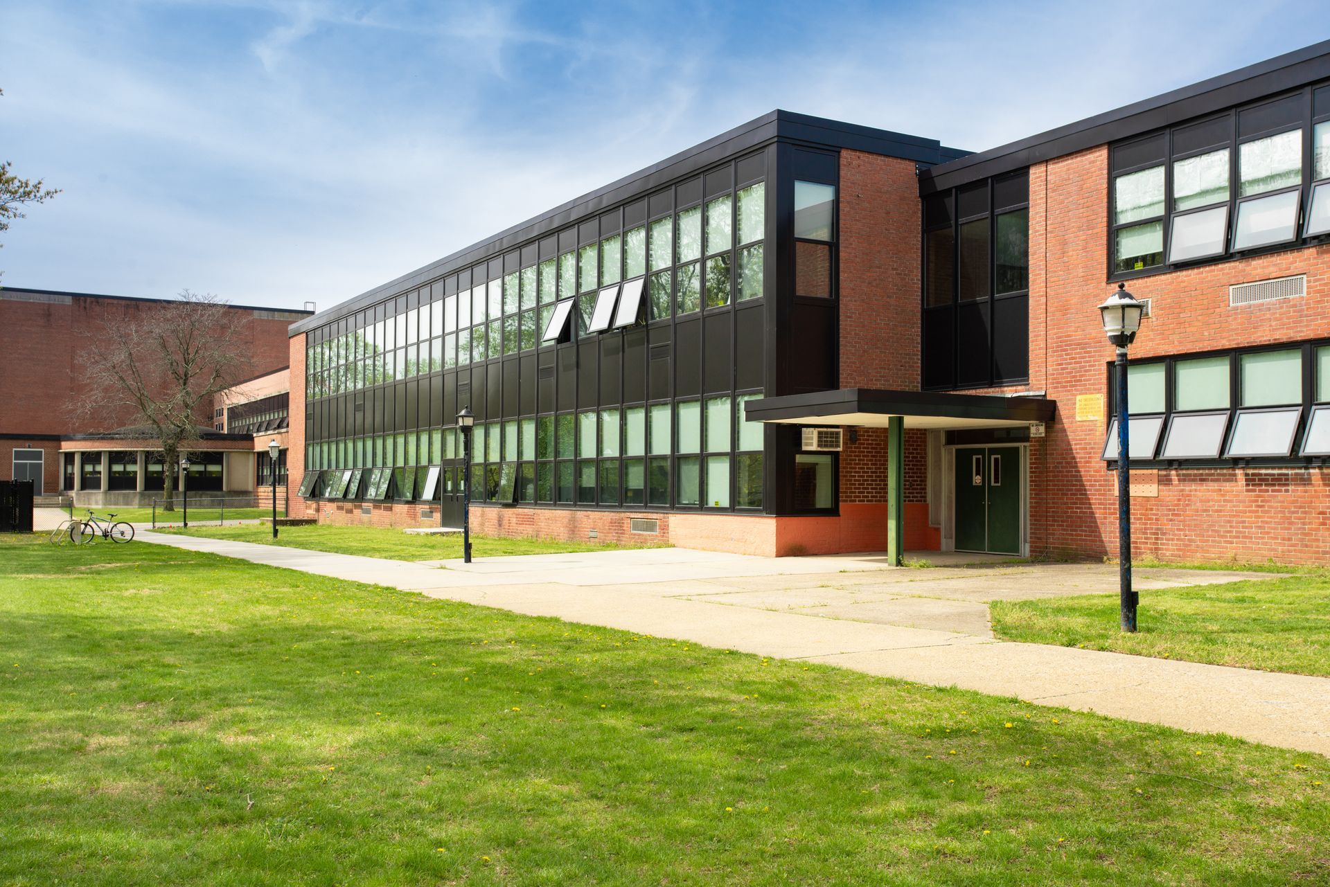 A large brick building with a lot of windows is sitting on top of a lush green field.