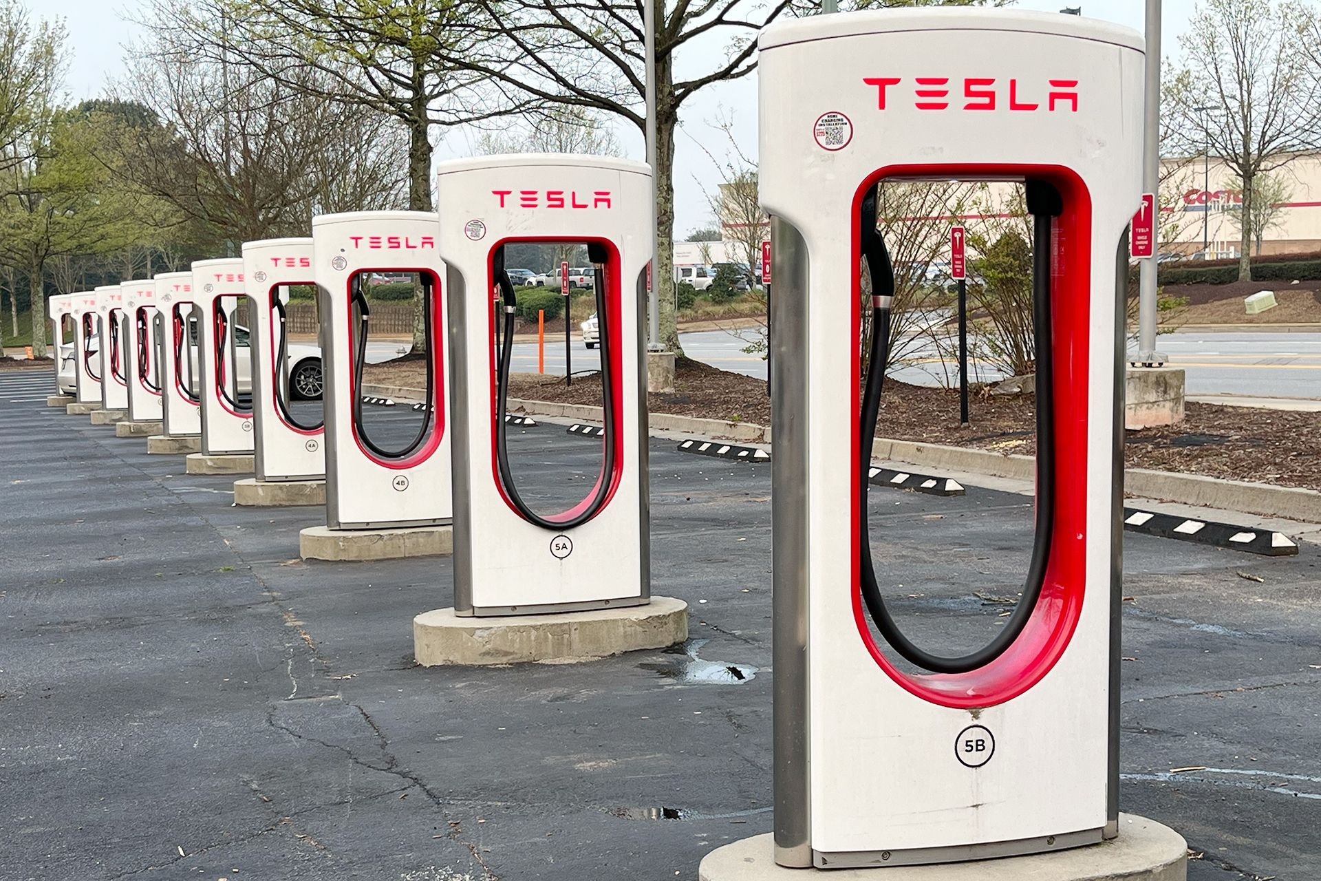 A row of tesla charging stations are lined up in a parking lot.