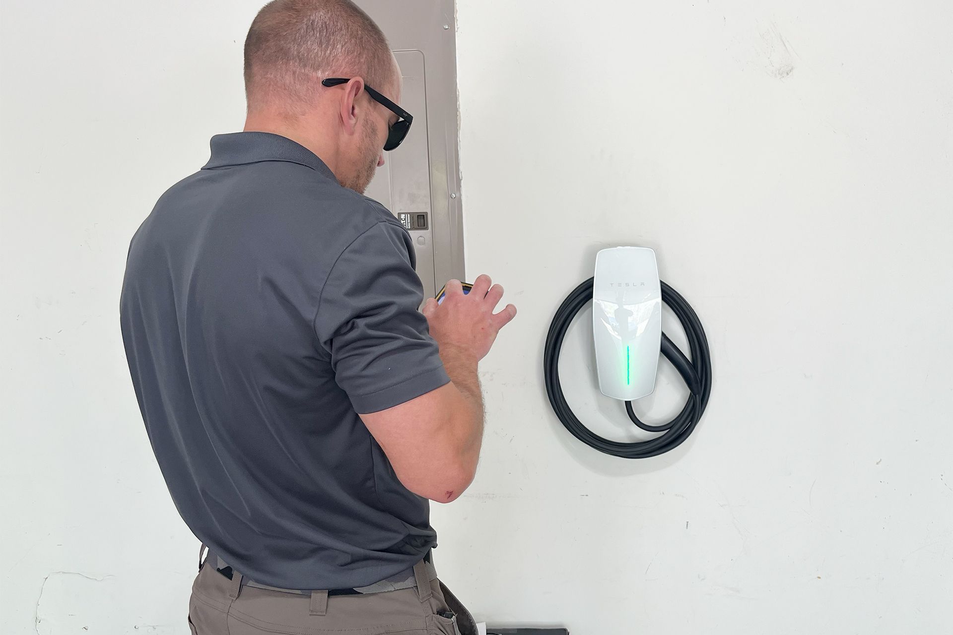 A man is installing a tesla charging station on a wall.