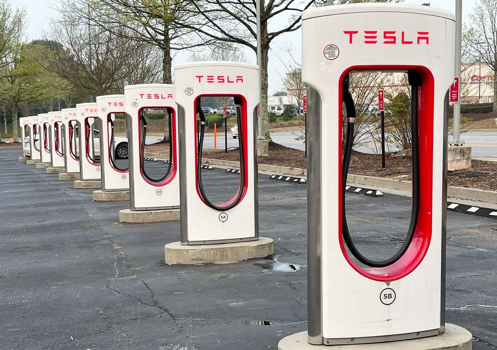 A row of tesla charging stations are lined up in a parking lot.