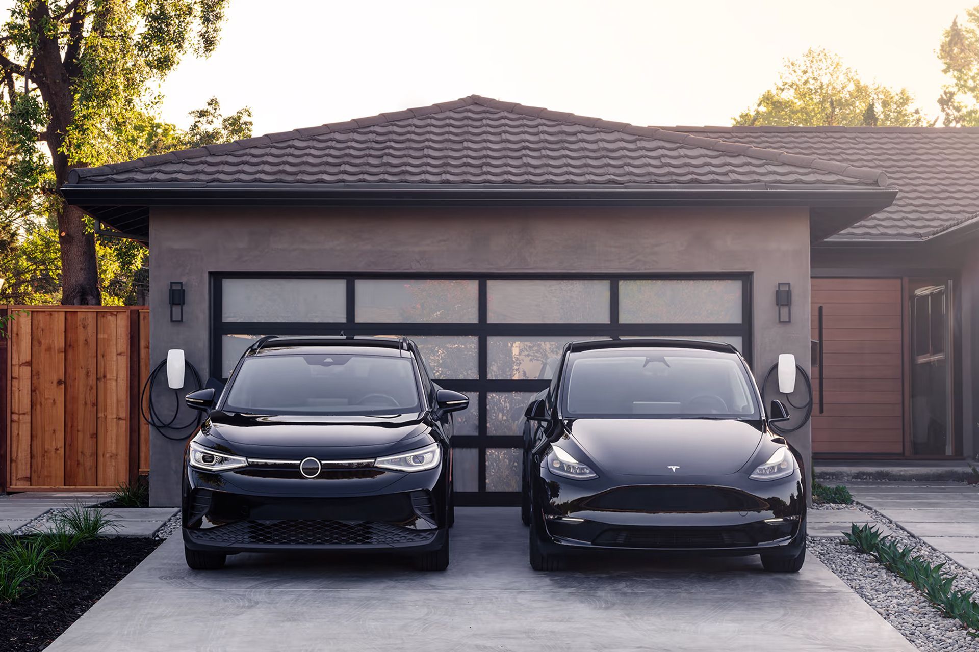 Two electric cars are parked in front of a house.